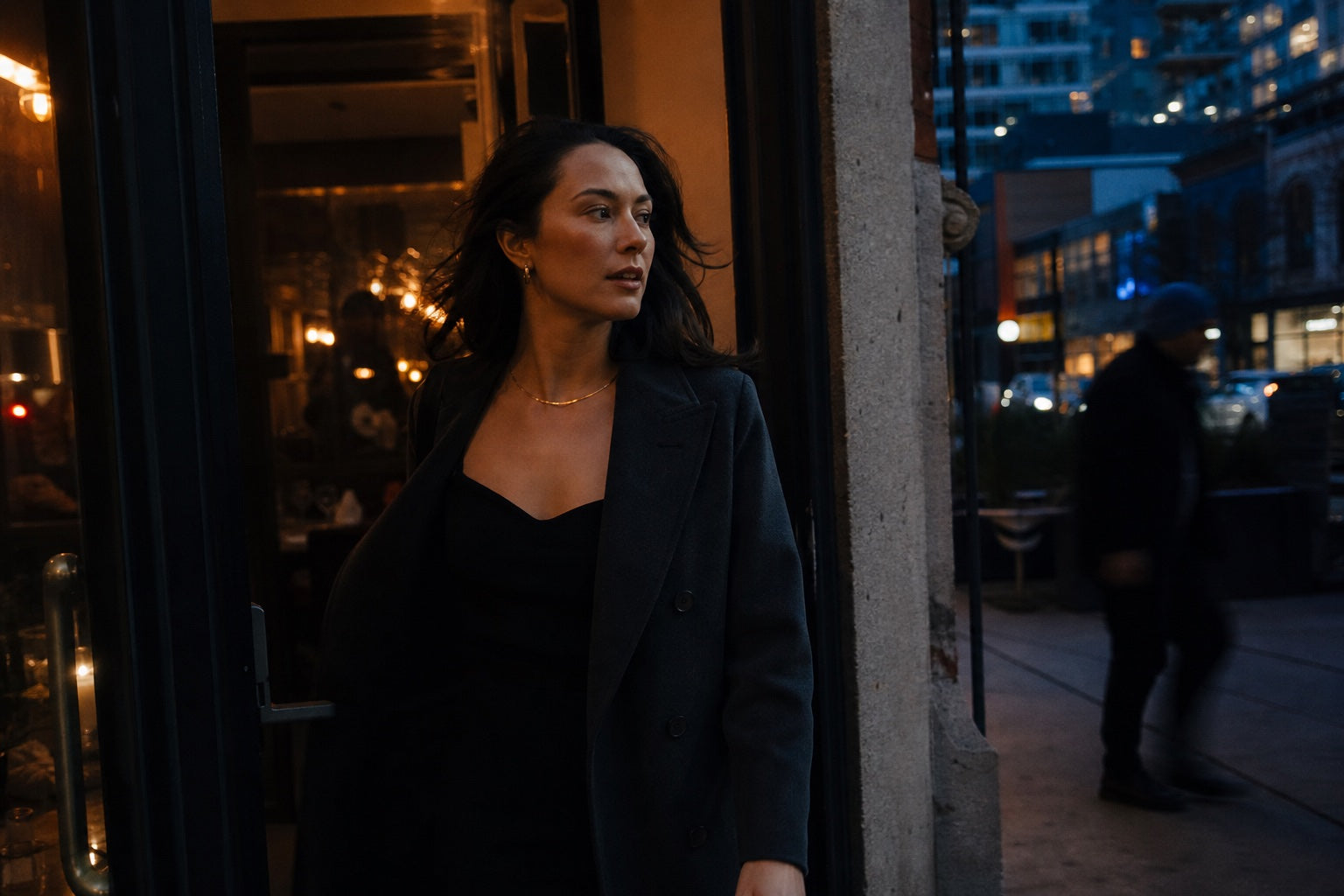 Woman wearing subtle jewelry outside a Toronto restaurant at dusk