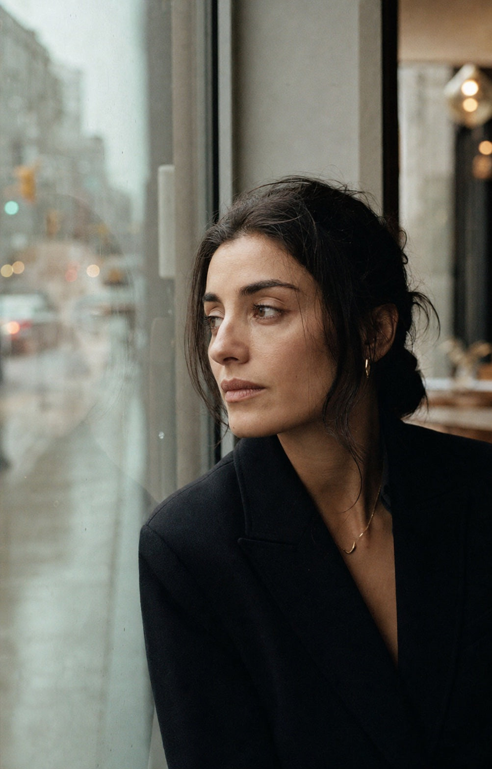 Woman wearing understated jewelry beside a Toronto café window